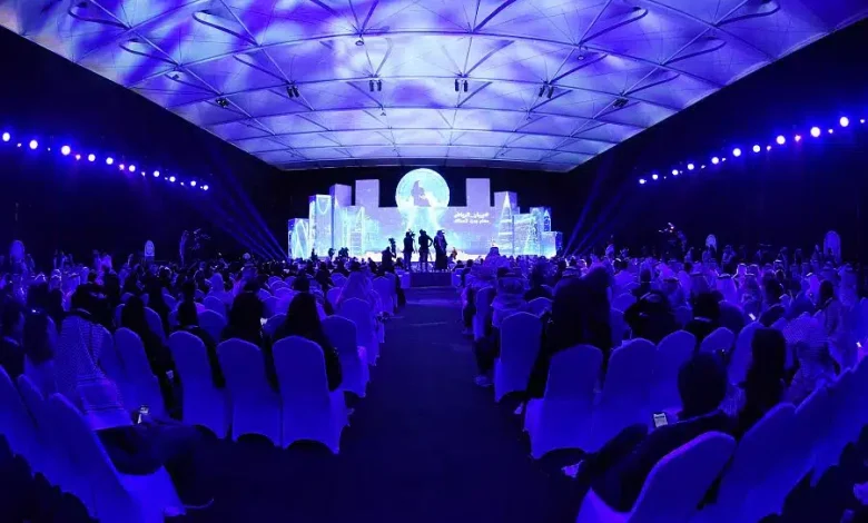 Biban 2025 Riyadh: Inside the Forum Turning Saudi Startups into Global Players 1 1 Blue-lit auditorium at Biban 2025 in Riyadh, filled with rows of delegates facing a stage with a large circular screen and cityscape-style set design.”