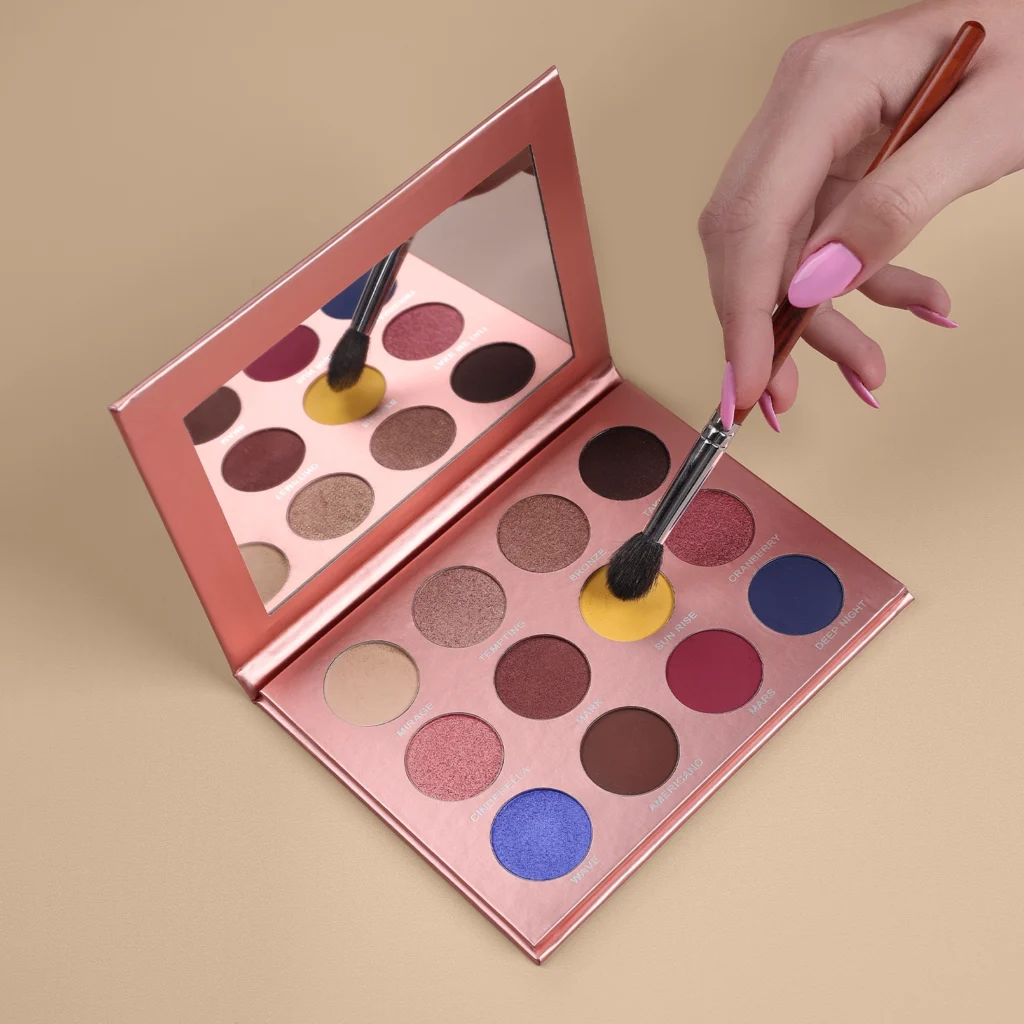 Zaza Bajouk Is the Middle East’s #1 Fashion Icon in 2025 1 1 Flatlay of pink-toned beauty products, including lip glosses, a pencil and a sculpted white tube, arranged on stacked pastel boxes against a soft pink background.