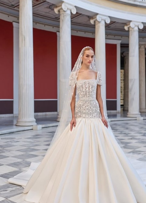 Elegant bride on runway in strapless white gown with laser-cut floral details and statement headpiece at a luxury bridal show