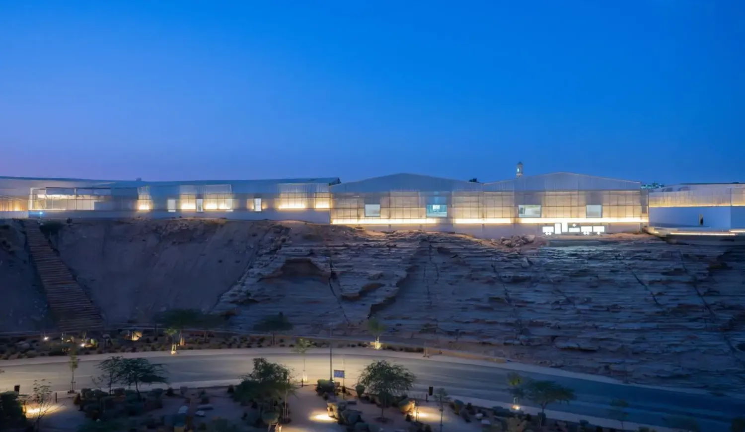 Exterior night view of the Diriyah Contemporary Art Biennale venue built into the desert landscape in Saudi Arabia.