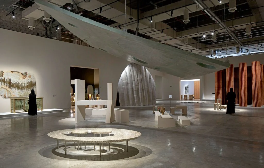 Interior view of a contemporary museum gallery featuring large-scale installations and sculptural furniture in an open exhibition hall.