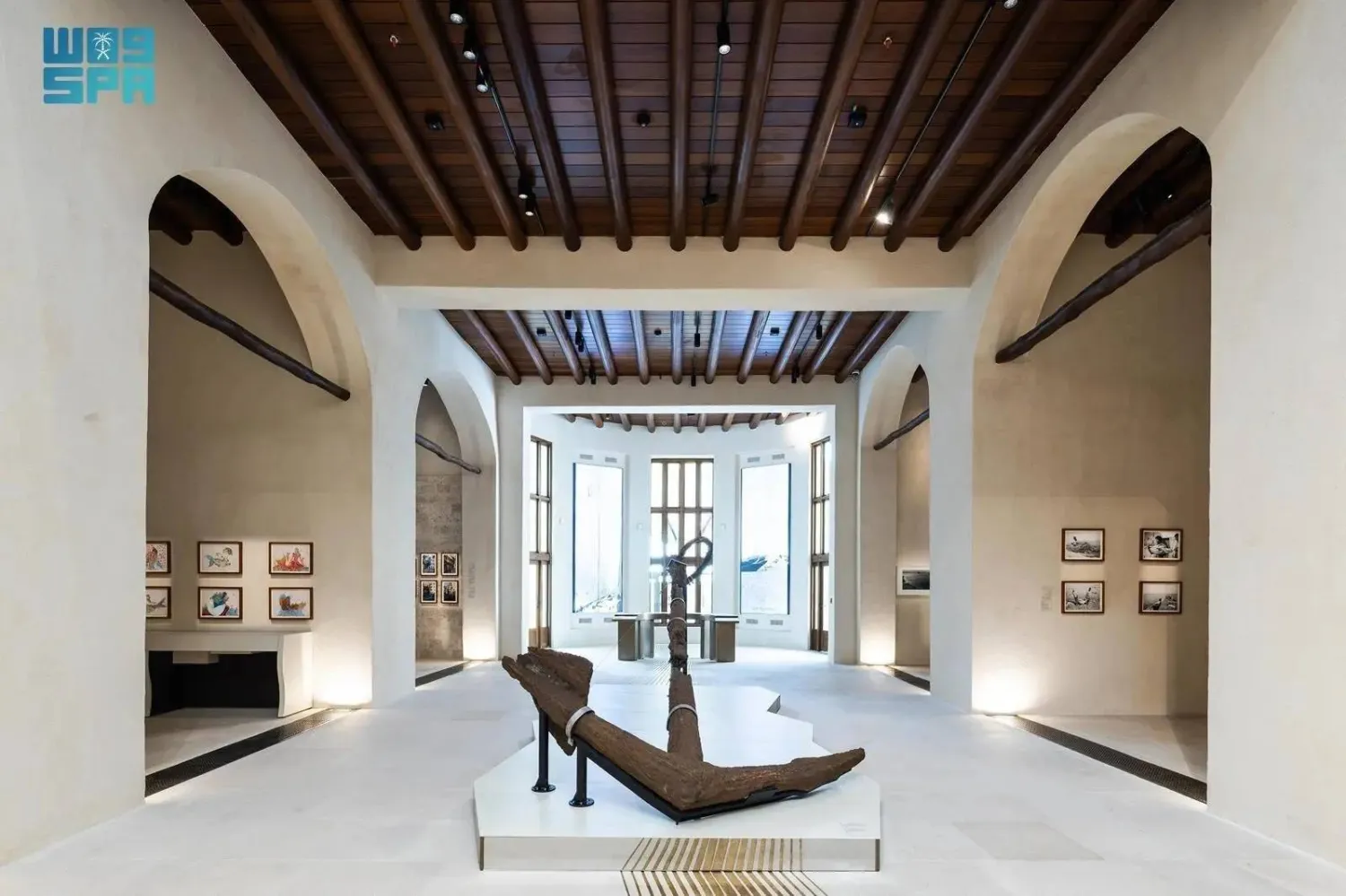 Jeddah Red Sea Museum January Cultural Program: Full Schedule and Highlights 1 1 Wide interior view of a museum gallery with white arches, wooden ceiling beams, framed artworks on the walls, and a large anchor displayed on a central platform.