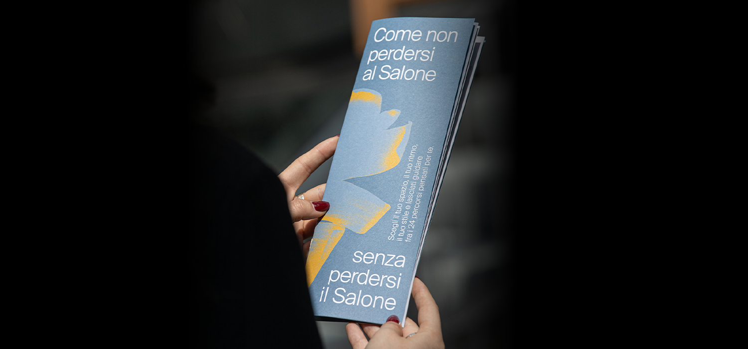 Visitor holding a Salone del Mobile guide brochure, highlighting curated itineraries and personalized design journeys through the Milan exhibition