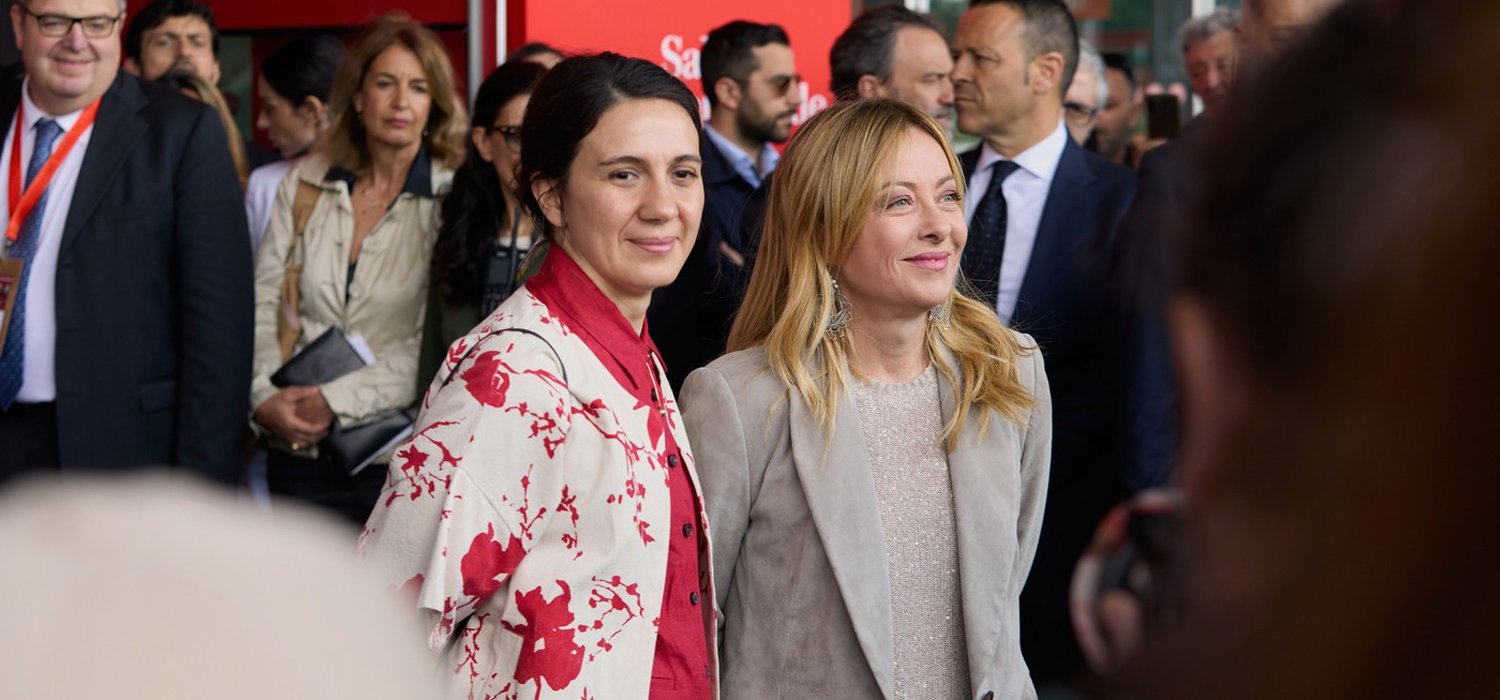 Two women attending the Salone del Mobile Milan opening ceremony, surrounded by guests and officials at the international design event.